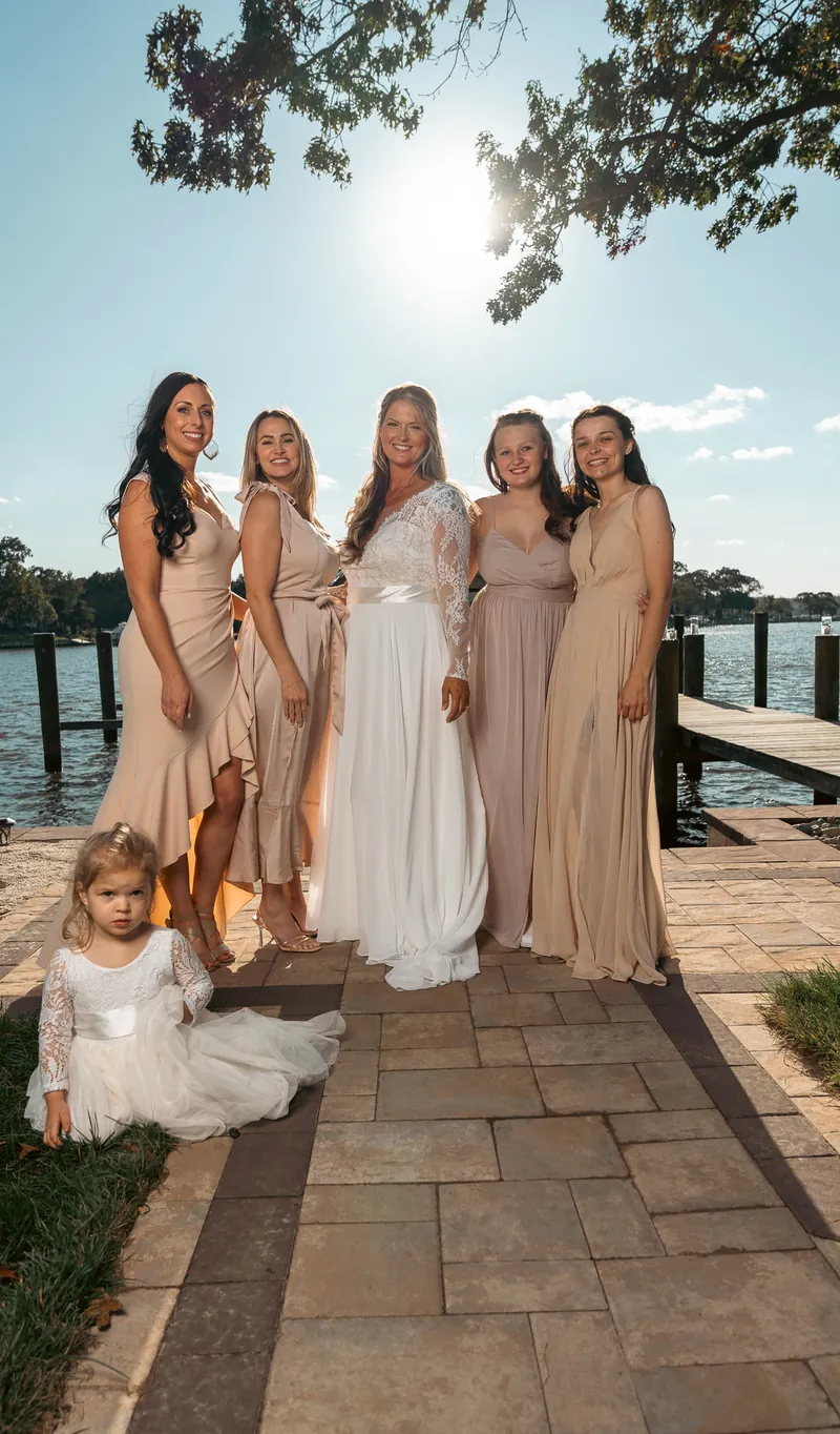 The bride and her bridesmaids on the paver path, sun overhead — Annapolis