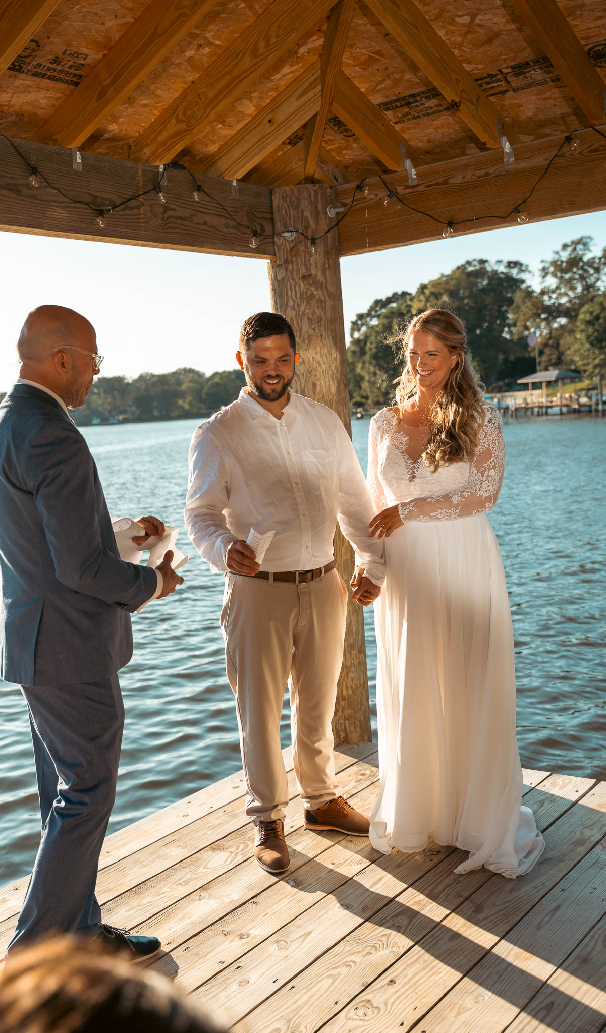 Waterfront ceremony under the boathouse roof — backyard wedding in Annapolis, Maryland