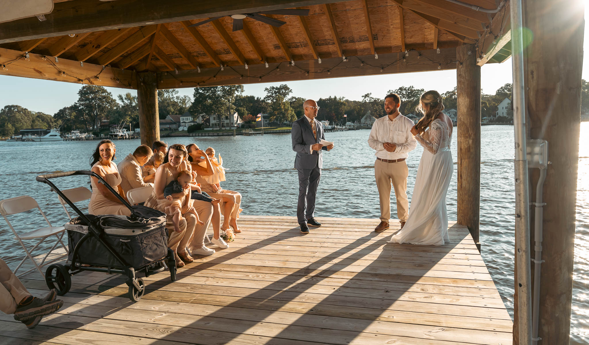 Waterfront ceremony under the boathouse roof — backyard wedding in Annapolis, Maryland