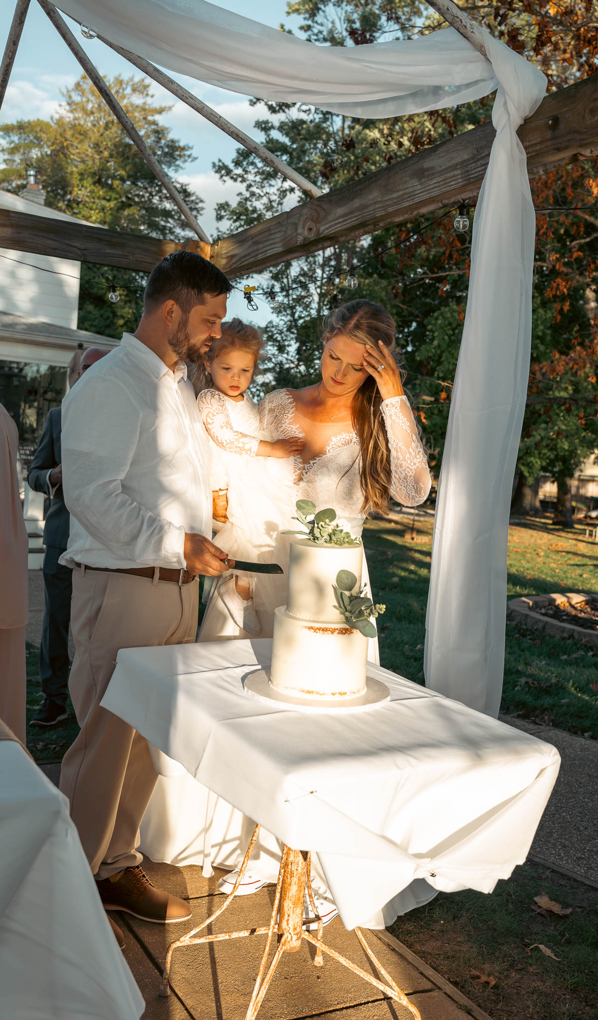 Bride and groom cutting the cake under the pergola — backyard wedding in Annapolis, Maryland