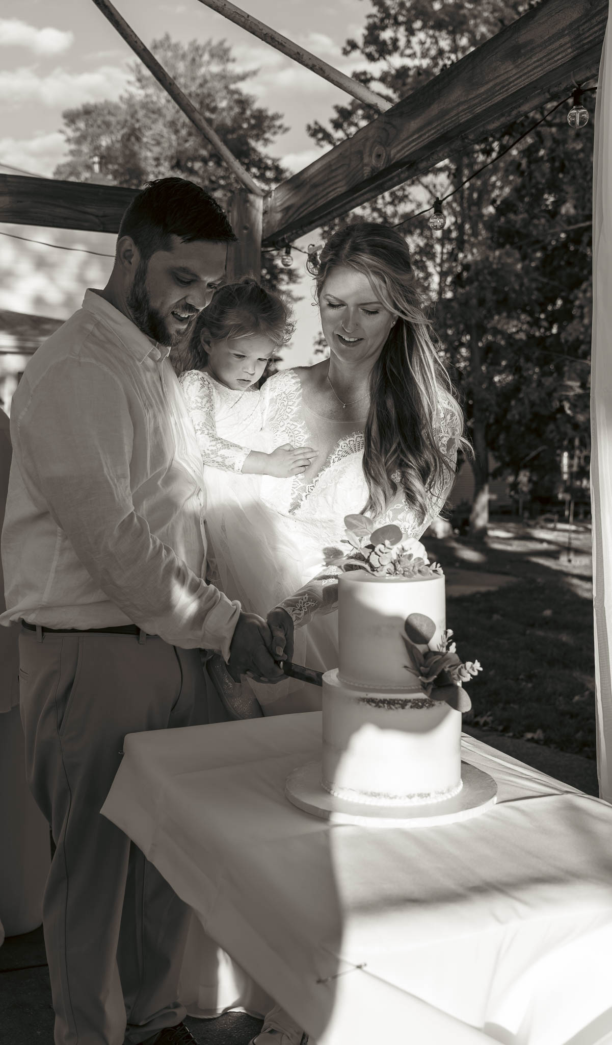 The couple cutting their wedding cake outdoors — backyard wedding in Annapolis, Maryland