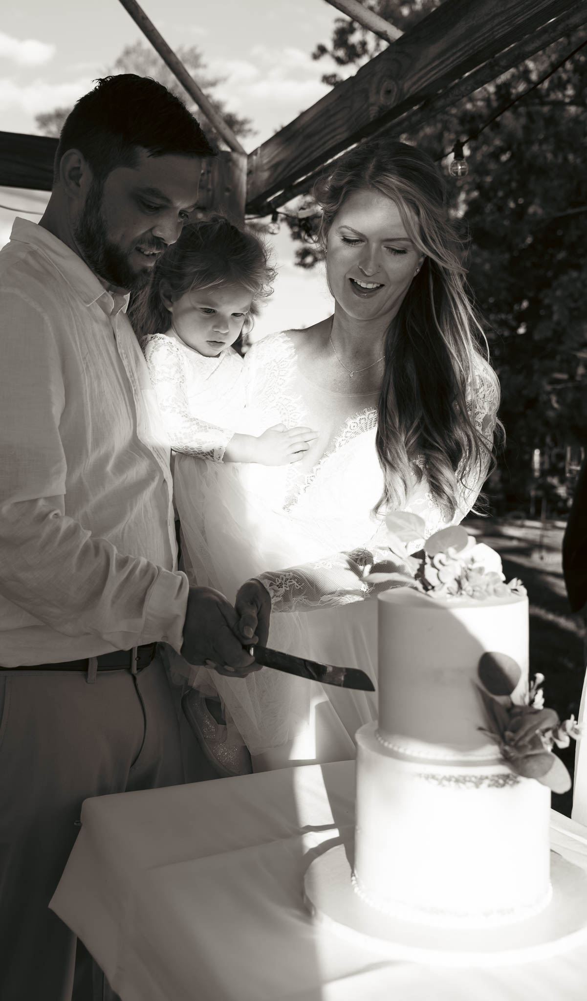 Bride and groom cutting the cake under the pergola — backyard wedding in Annapolis, Maryland