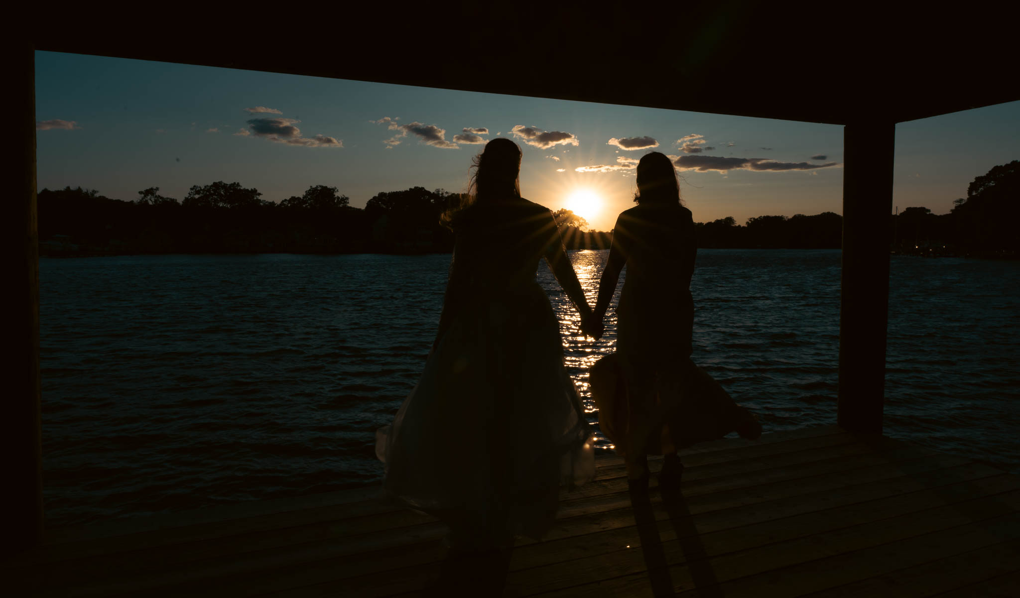 Bride and groom silhouetted against the sunset over the creek — backyard wedding in Annapolis, Maryland